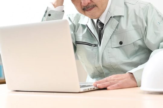 ノートPCで作業する男性経営者